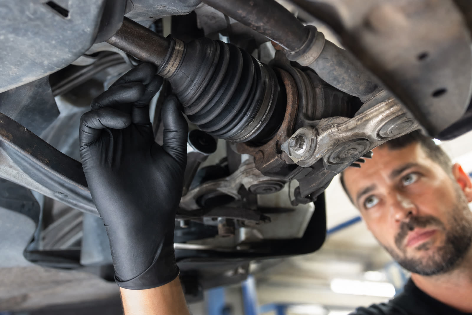 Perry's Quality Auto mechanic inspecting a CV axle and rubber CV boot on a vehicle in Simi Valley
