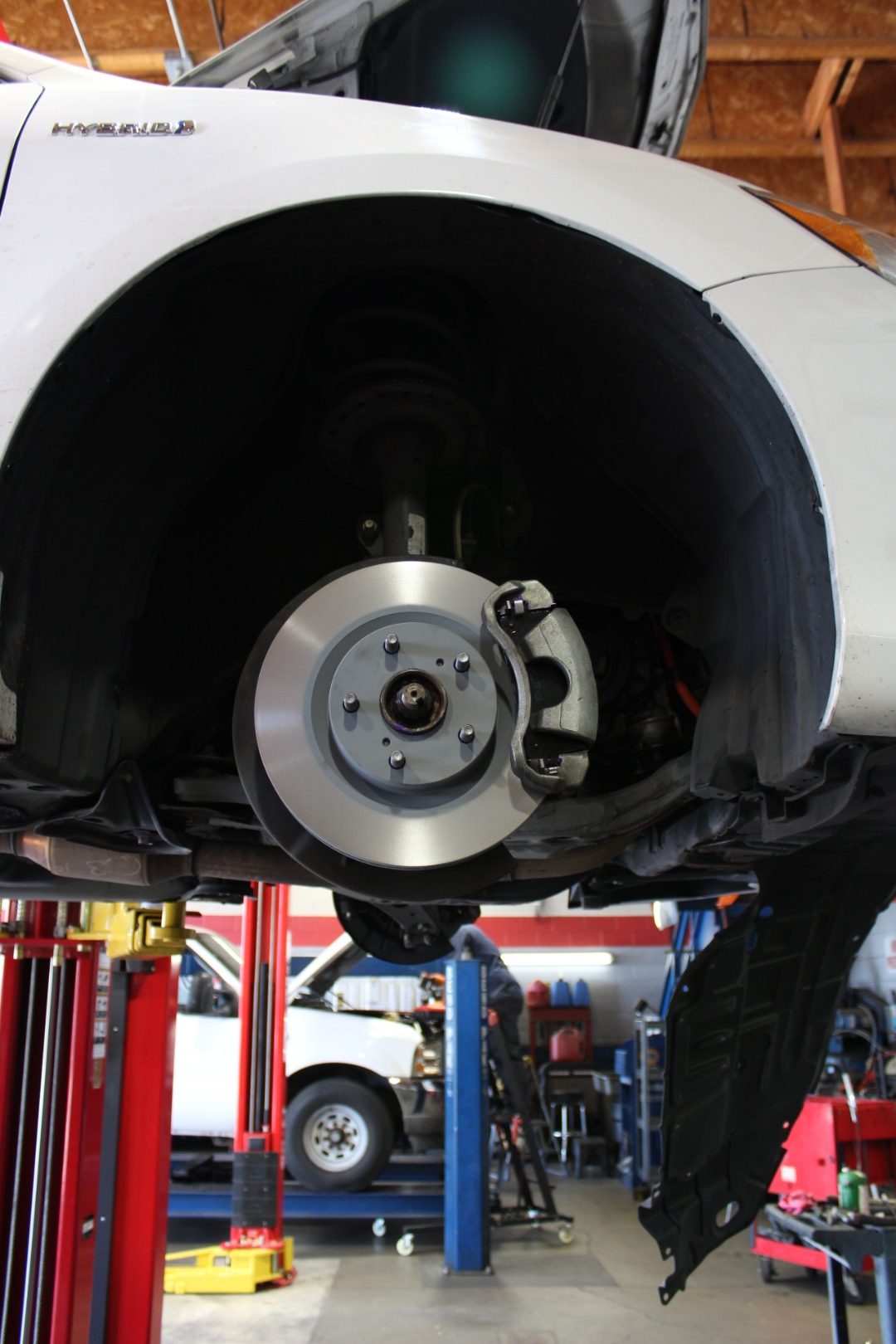 Fresh brake rotor and caliper on a hybrid sedan in for brake service