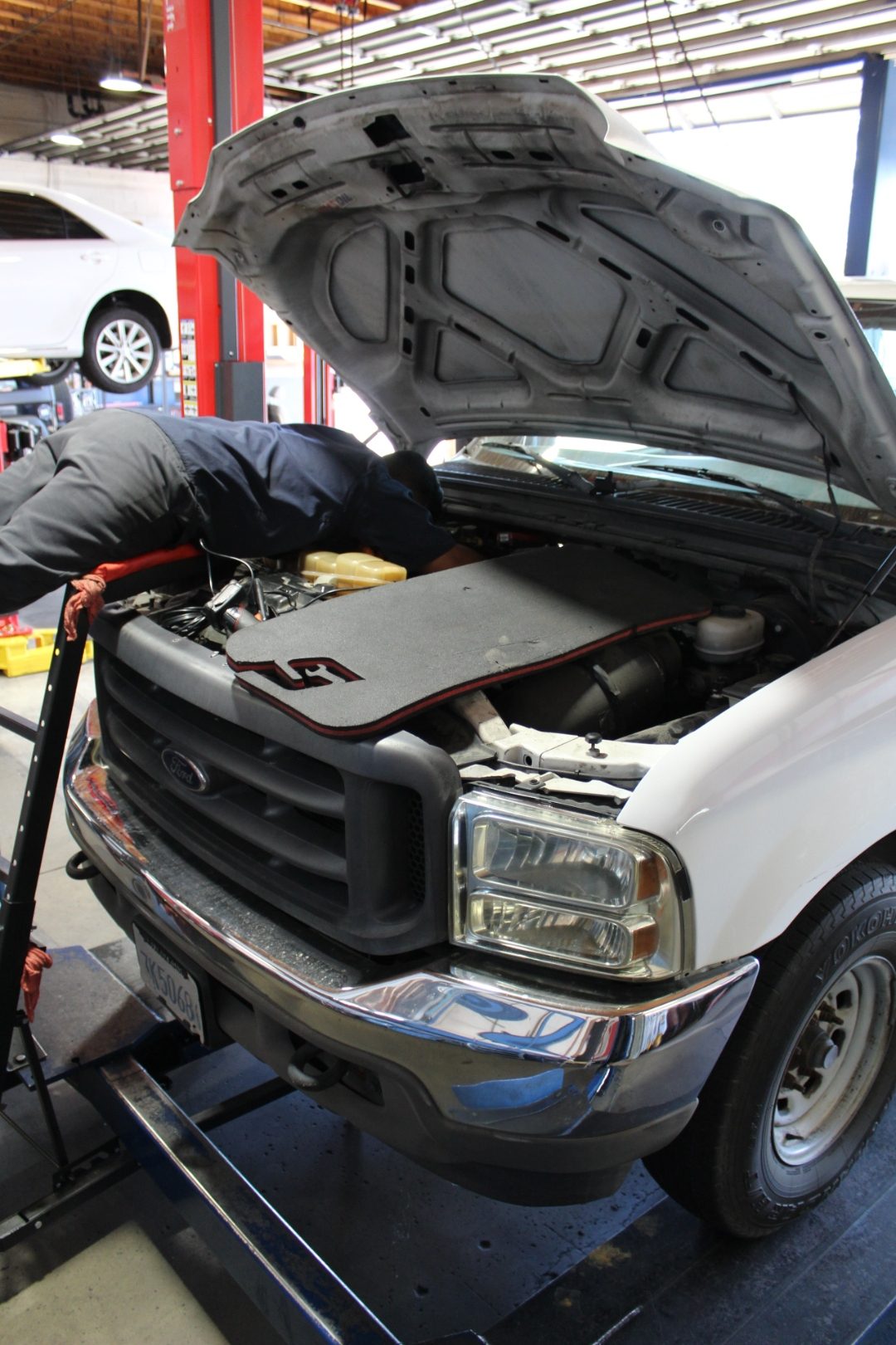 Perry's technician working under the hood of a Ford truck on the lift