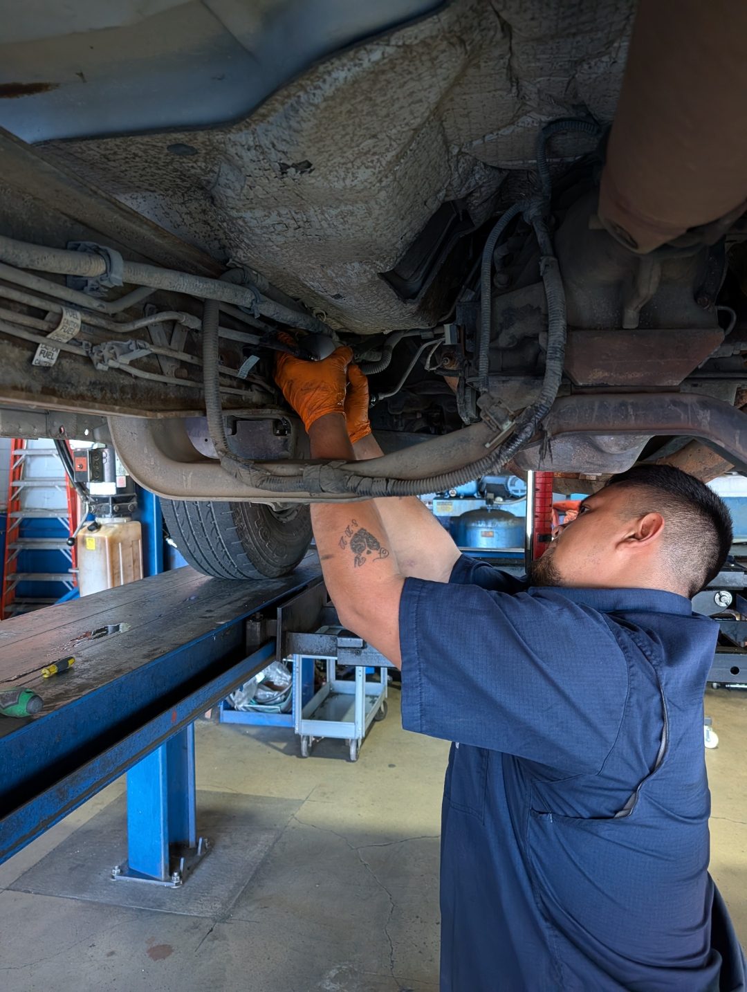 Perry's technician working on a vehicle's undercarriage on the alignment lift
